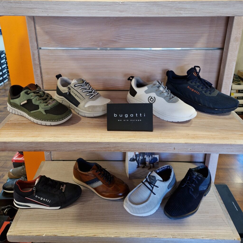 Plusieurs paires de chaussures Bugatti pour homme: sneakers et ville. Présentées sur étagères en bois clair. Logo 'bugatti we are europe'.