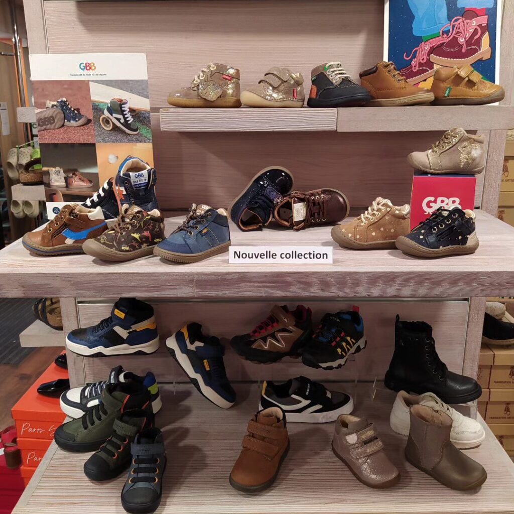 Présentoir de chaussures enfants GBB et Geox. Divers modèles et couleurs: baskets, bottines, nouvelle collection. Sur plusieurs étagères.